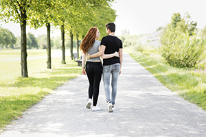 Teen couple lovingly walking arm in arm down a path