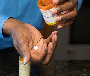 Closeup of man's hands holding prescription pill and pill bottle.